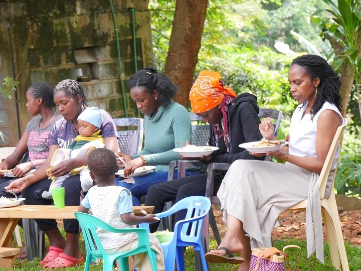 Women and children sitting in the garden eating plates of food together